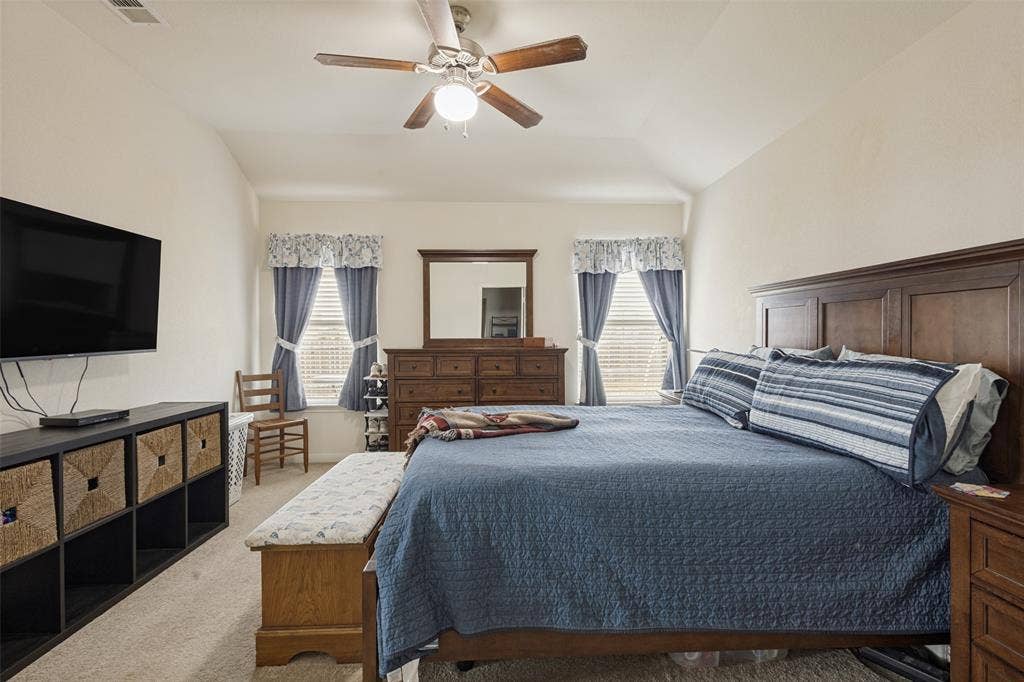 Vaulted ceiling featuring a central multi-blade ceiling fan with integrated lighting and dual windows