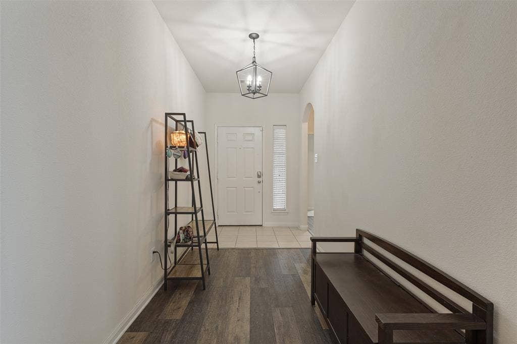 Entryway featuring wood-finish plank flooring, ceramic tile flooring, a geometric pendant light fixture, and an arched doorway
