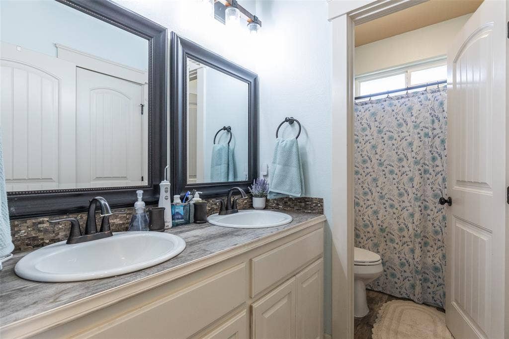 Double vanity featuring a wood-finish countertop, dual under-mount sinks, dark-toned faucets, and framed wall mirrors