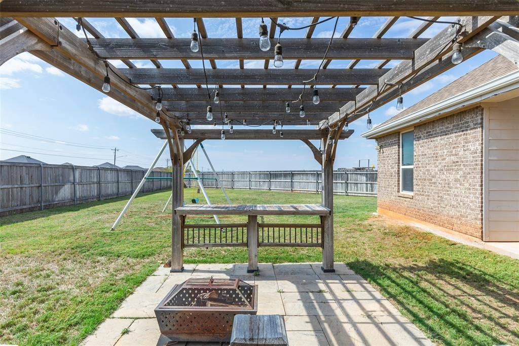 Backyard featuring a wooden pergola with integrated string lighting, a built-in counter, and a concrete paver patio