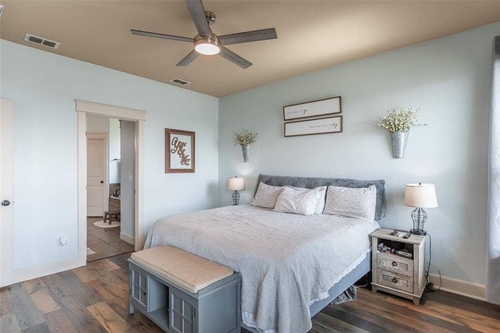 Bedroom featuring wood-finish flooring, a multi-tonal ceiling, and a central ceiling fan with integrated lighting
