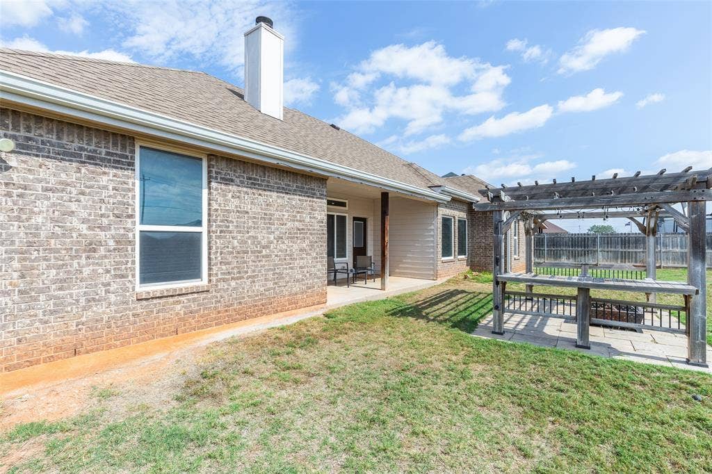 Brick exterior featuring a covered patio, a stone-paver patio area, and a timber pergola