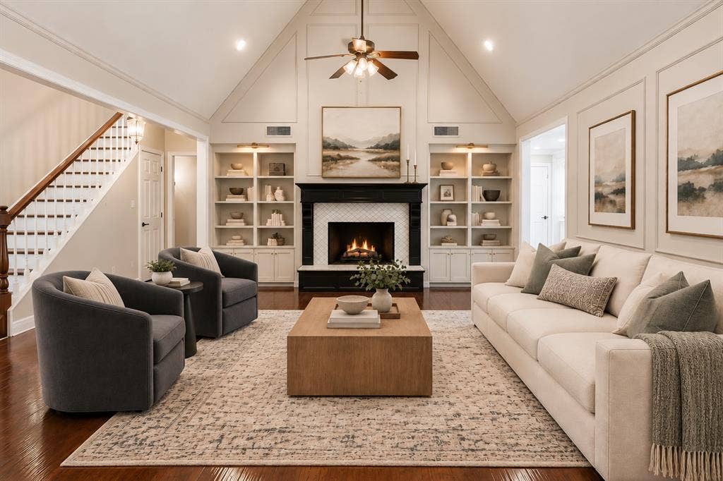 Living area featuring a vaulted ceiling with panel molding, built-in floor-to-ceiling shelving, a fireplace with a decorative mantle, and wood-finish flooring