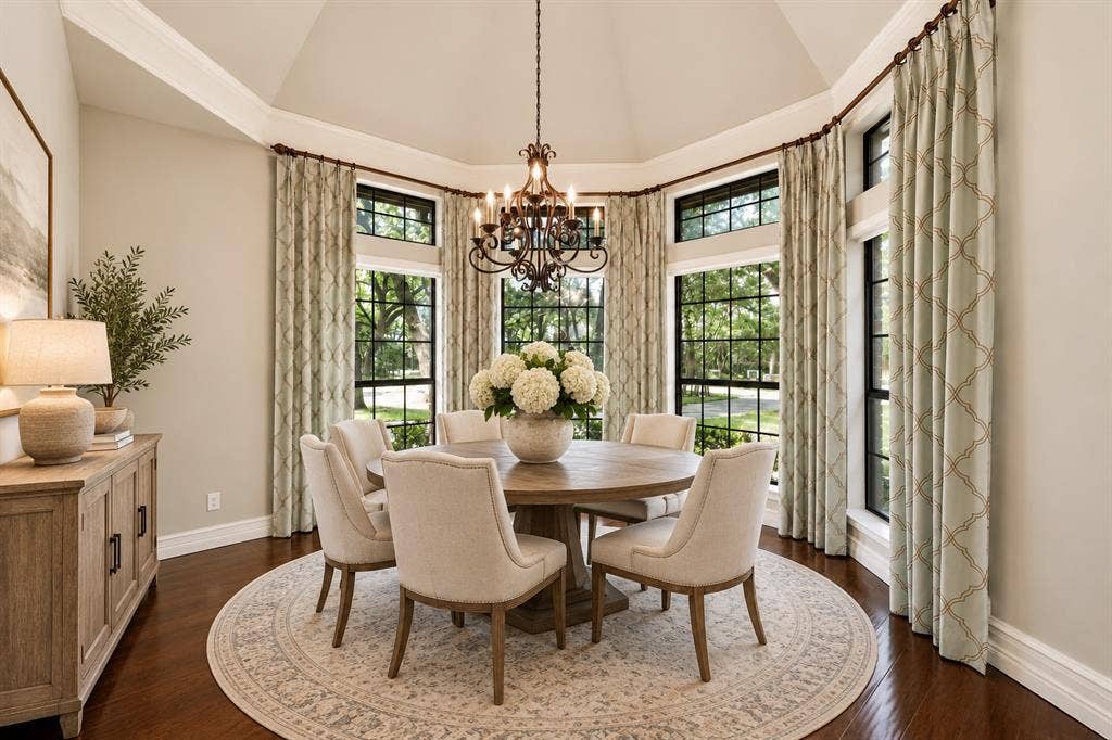 Octagonal room featuring a vaulted ceiling, wood-finish flooring, floor-to-ceiling windows with dark framing, and a decorative metal chandelier
