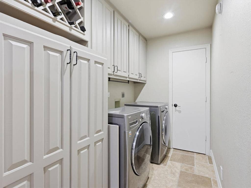 Custom cabinetry with integrated wine storage, upper and lower storage units, and stone-tile flooring