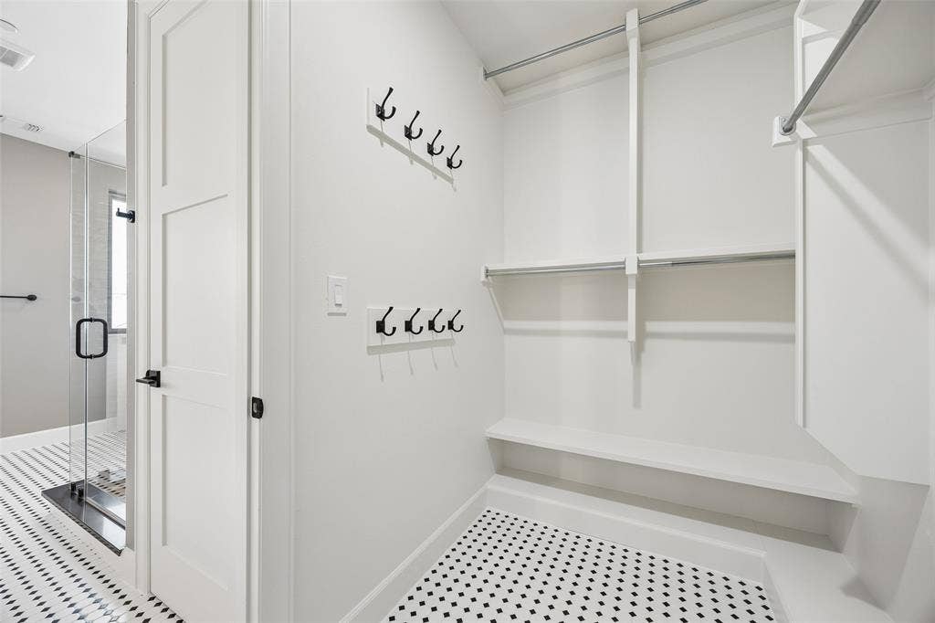 Walk-in closet featuring white built-in shelving, dual-tier hanging rods, and mounted hardware hooks