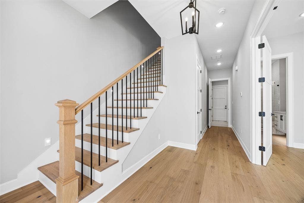 Staircase featuring wood-finish treads, a square newel post, and matte black metal balusters