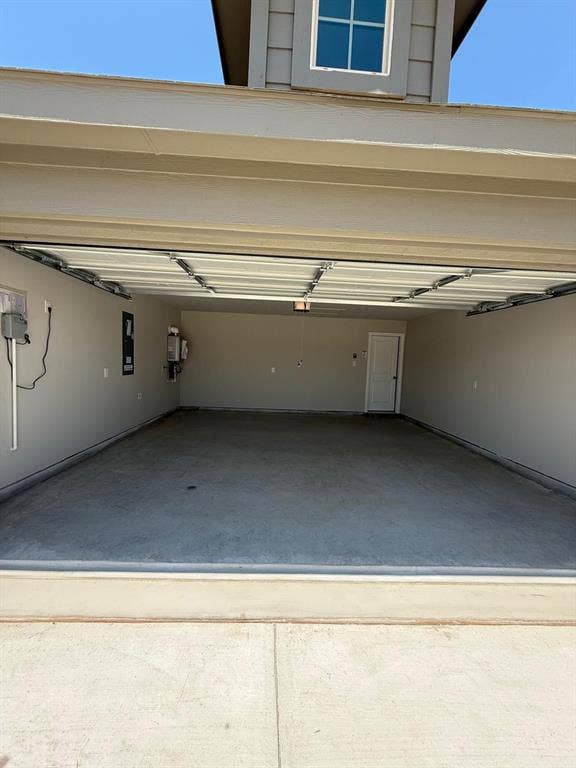Multi-car garage featuring a concrete floor, finished walls, overhead door system, and a dedicated interior door