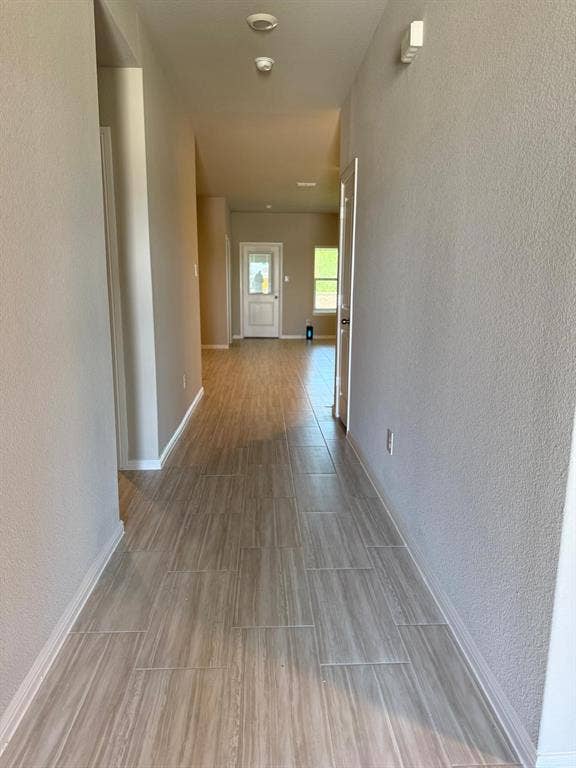 Hallway featuring wood-finish tile flooring, neutral wall paint, and an exterior door with glass insert