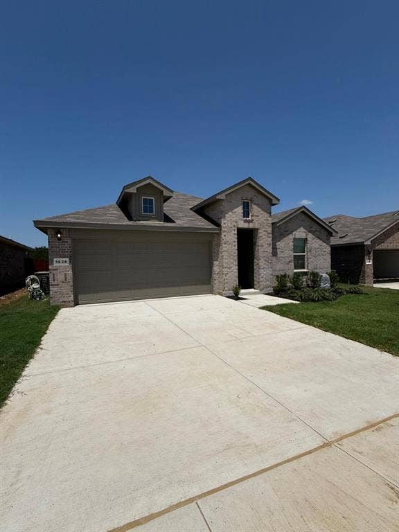 Brick exterior featuring a multi-gabled roofline, concrete driveway, and dormer window
