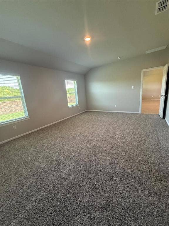 Neutral interior space featuring vaulted ceilings, neutral wall tones, plush wall-to-wall carpeting, and double-pane windows with horizontal blinds
