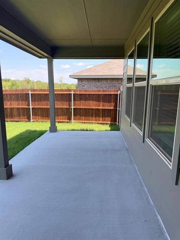Covered concrete patio with horizontal wood-style fencing and rear lawn