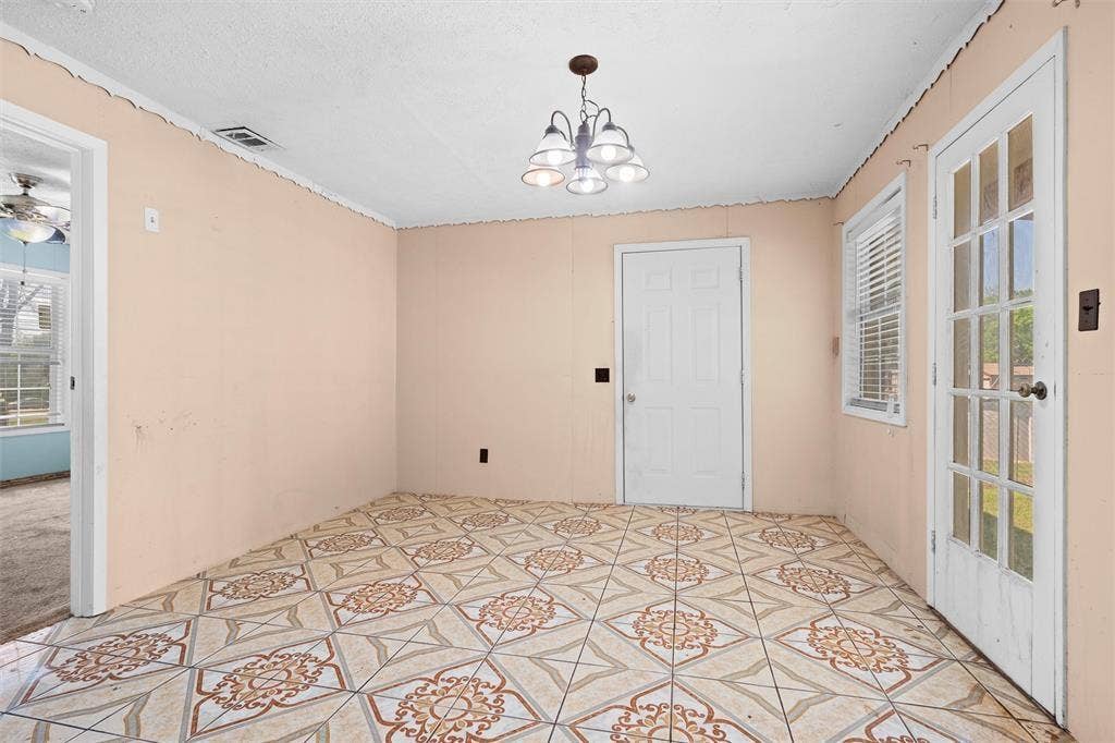 3401 E University Drive, McKinney, TX 75069 Room featuring patterned tile flooring, a multi-light chandelier, a glass-paneled exterior door, and a six-panel interior door