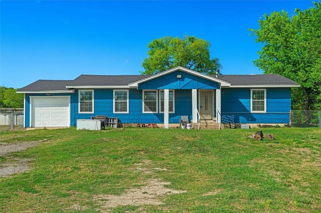 3401 E University Drive, McKinney, TX 75069 Single-story residence featuring blue horizontal siding, a central covered porch with structural columns, an attached one-car garage, and a gable roof
