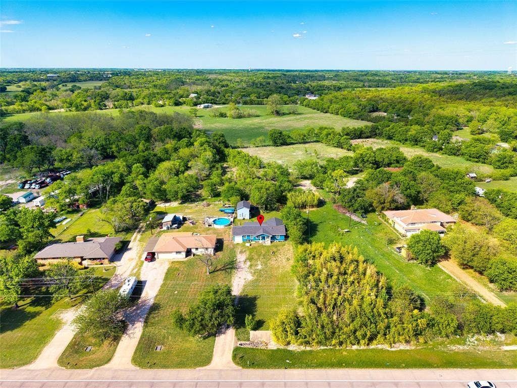 3401 E University Drive, McKinney, TX 75069 Aerial perspective of a property featuring extensive acreage, mature trees, and a paved road frontage