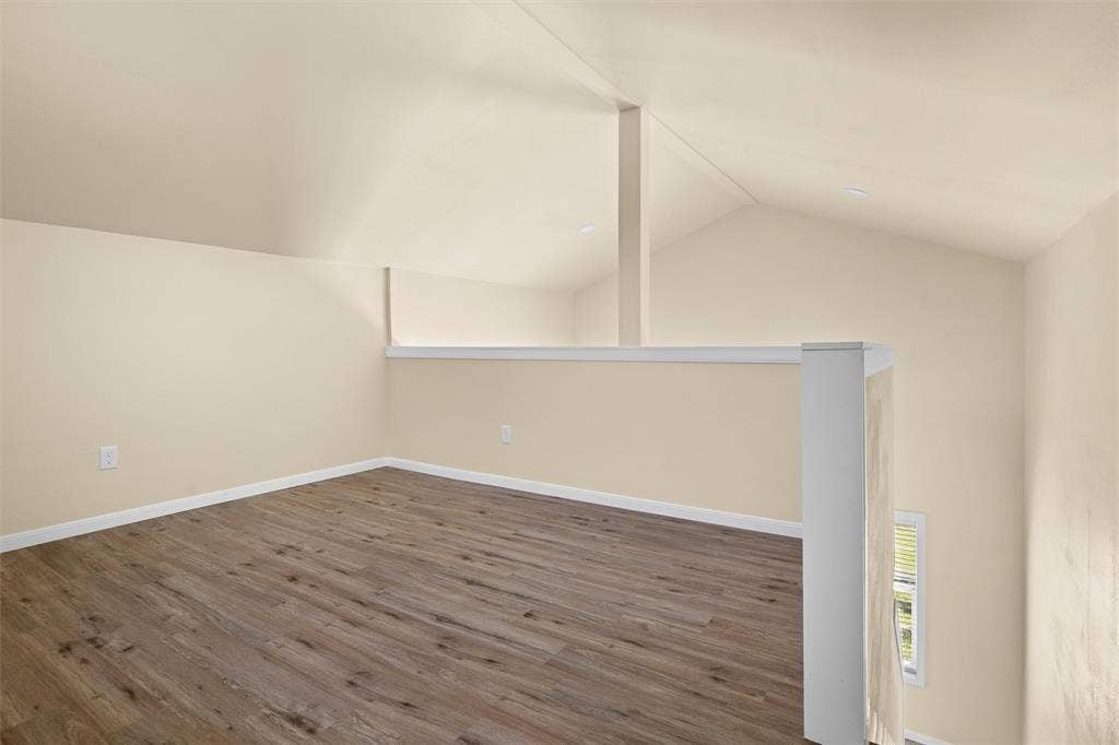 3401 E University Drive, McKinney, TX 75069 Vaulted ceiling, wood-finish flooring, and a white railing featuring a central support post