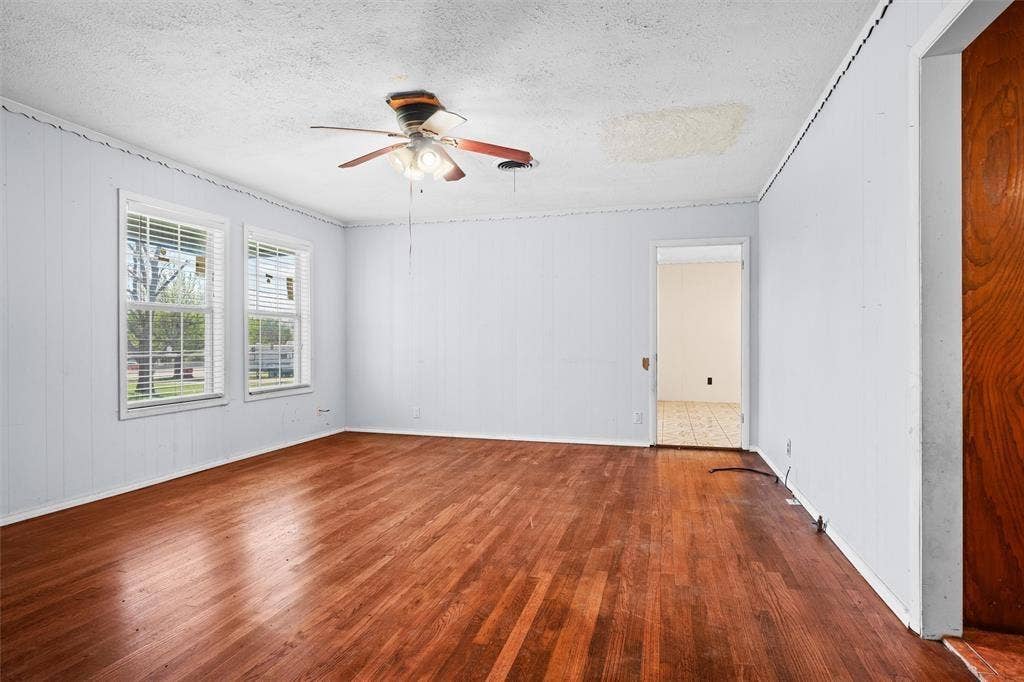 3401 E University Drive, McKinney, TX 75069 Interior space featuring wood-finish flooring, two large windows, and a ceiling-mounted light fixture with a fan