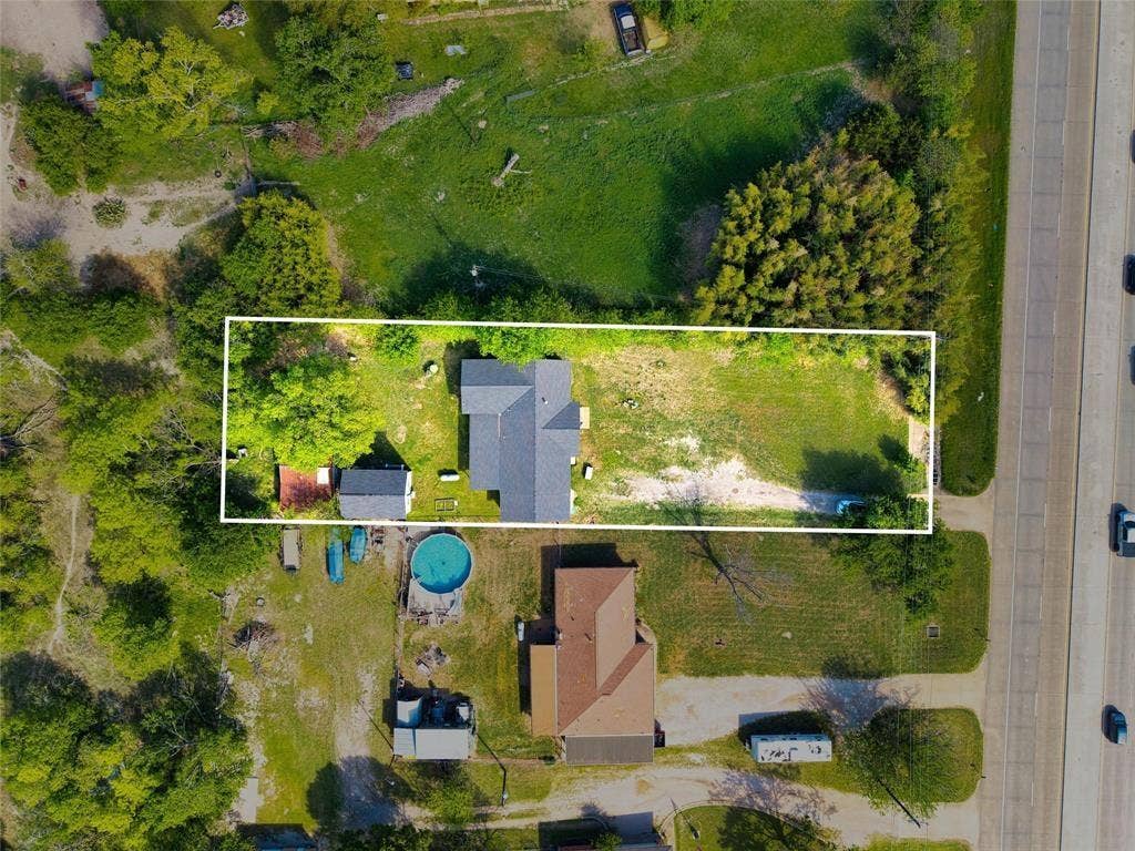 3401 E University Drive, McKinney, TX 75069 Aerial view of a rectangular lot featuring a detached residence, a secondary outbuilding, mature tree canopy, and open grounds