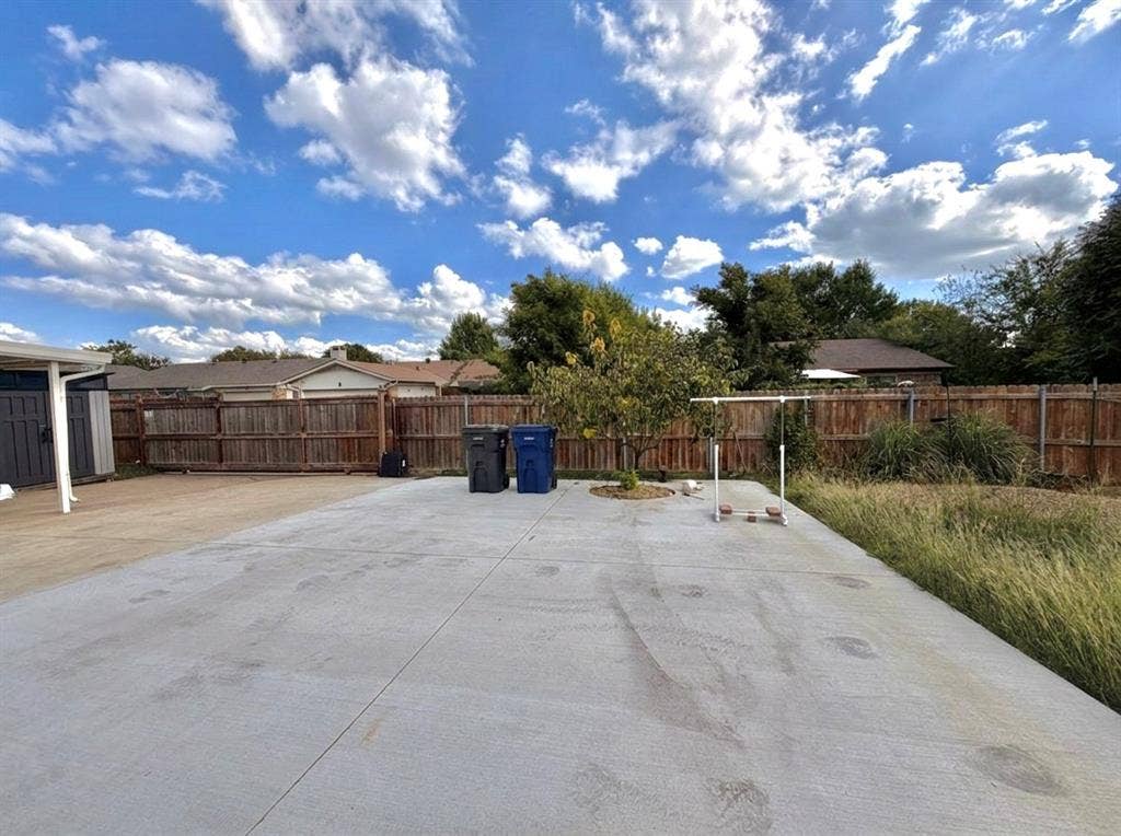 Expansive concrete patio featuring wood-paneled privacy fencing and a mature tree