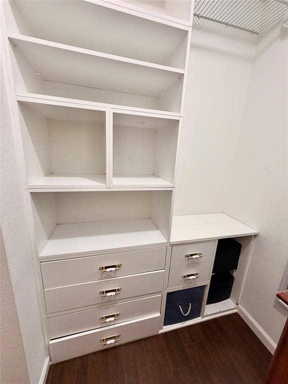 Custom white built-in shelving featuring four deep drawers, two open cubbies, and an integrated wire rack for overhead storage, finished with metallic hardware and wood-finish flooring