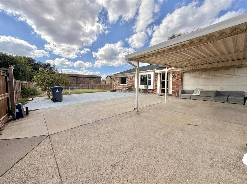 Exterior featuring a concrete driveway, attached metal carport, and a rear concrete patio