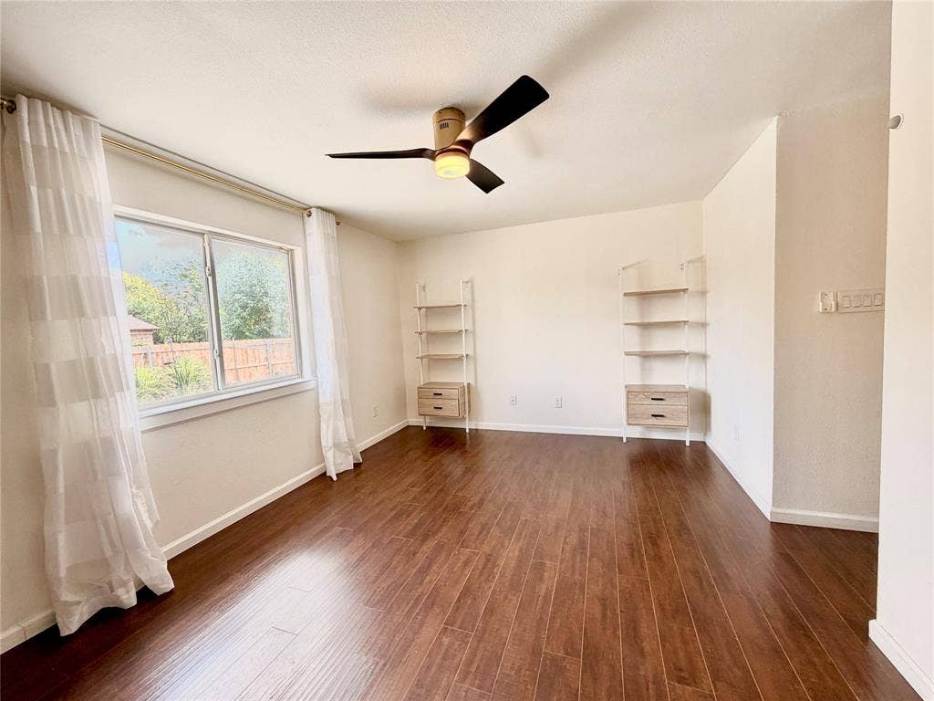 Wood-finish flooring, dual built-in wall shelving units with integrated storage drawers, and a ceiling fan with integrated lighting