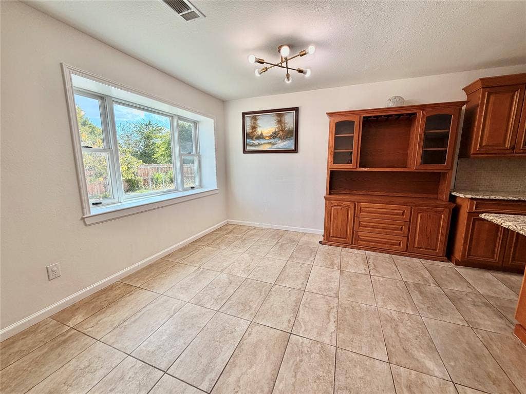 Large multi-pane window, tile flooring, built-in wooden cabinetry, and modern multi-arm ceiling light fixture