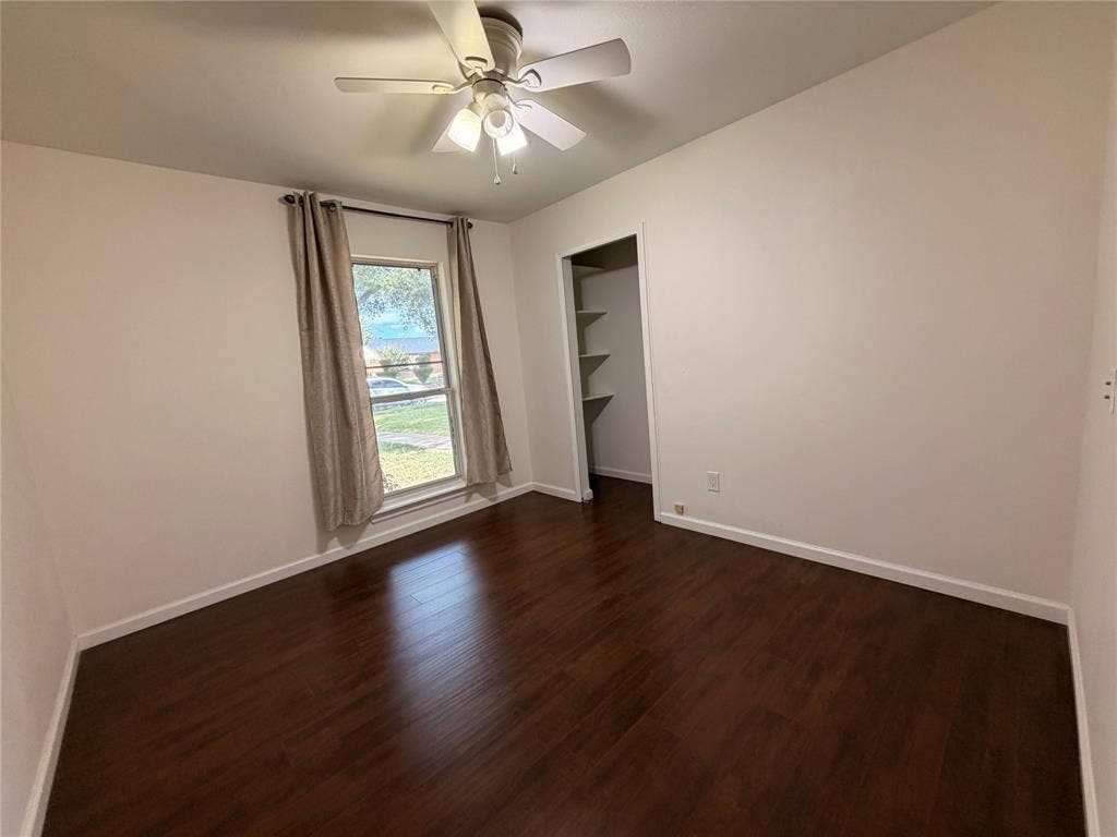 Interior space featuring wood-finish flooring, a ceiling fan with light fixture, a single window, and a built-in closet with shelving