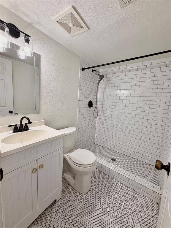 Bathroom featuring a white vanity cabinet with a light-toned countertop, subway tile shower surround, hexagonal tile flooring, and matte black plumbing fixtures