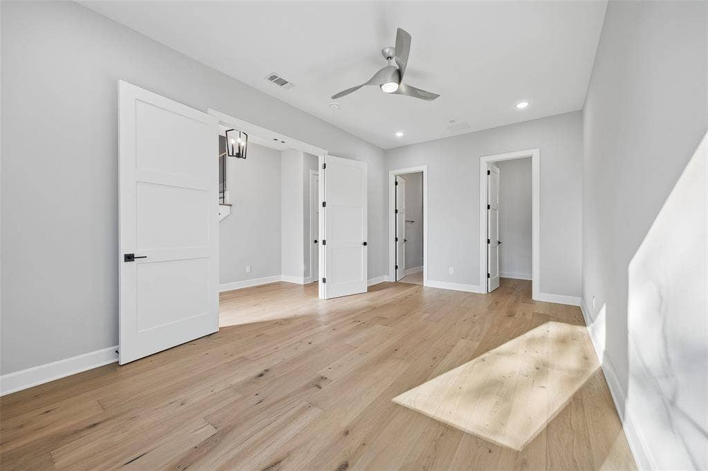 Interior room featuring wood-finish flooring, recessed lighting, a modern ceiling fan, and white three-panel interior doors with matte black hardware