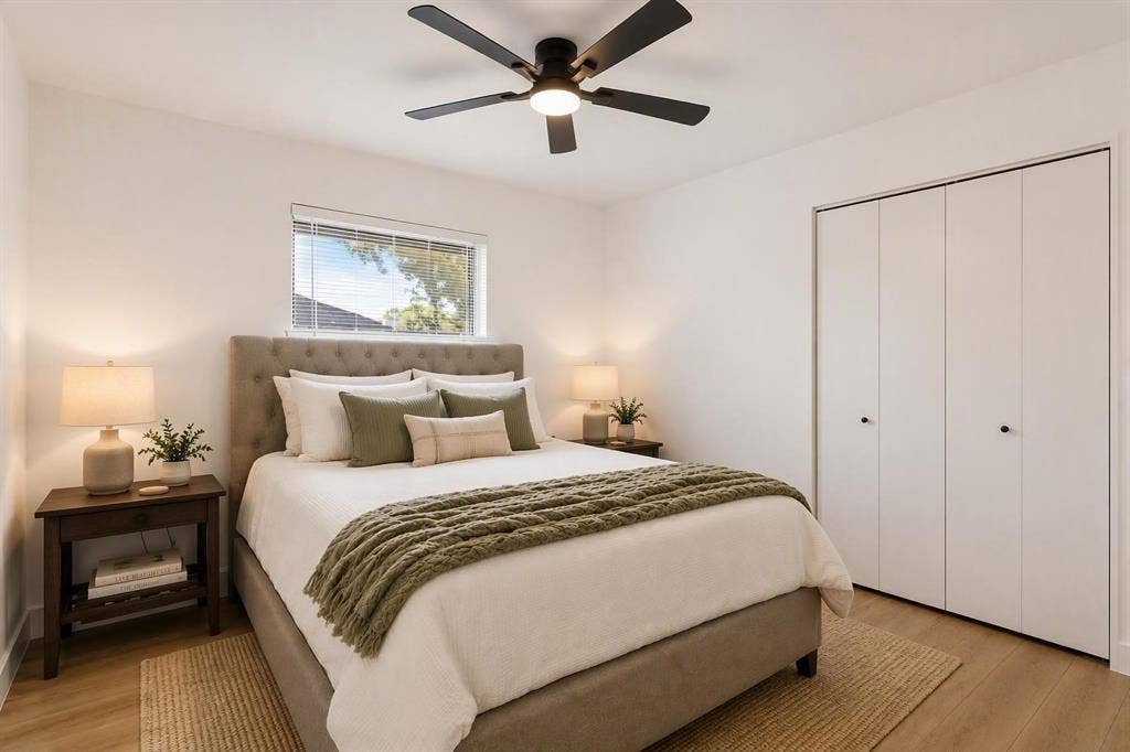 Neutral interior room featuring wood-finish flooring, a ceiling-mounted light fixture with a fan, and a built-in closet with multi-panel doors