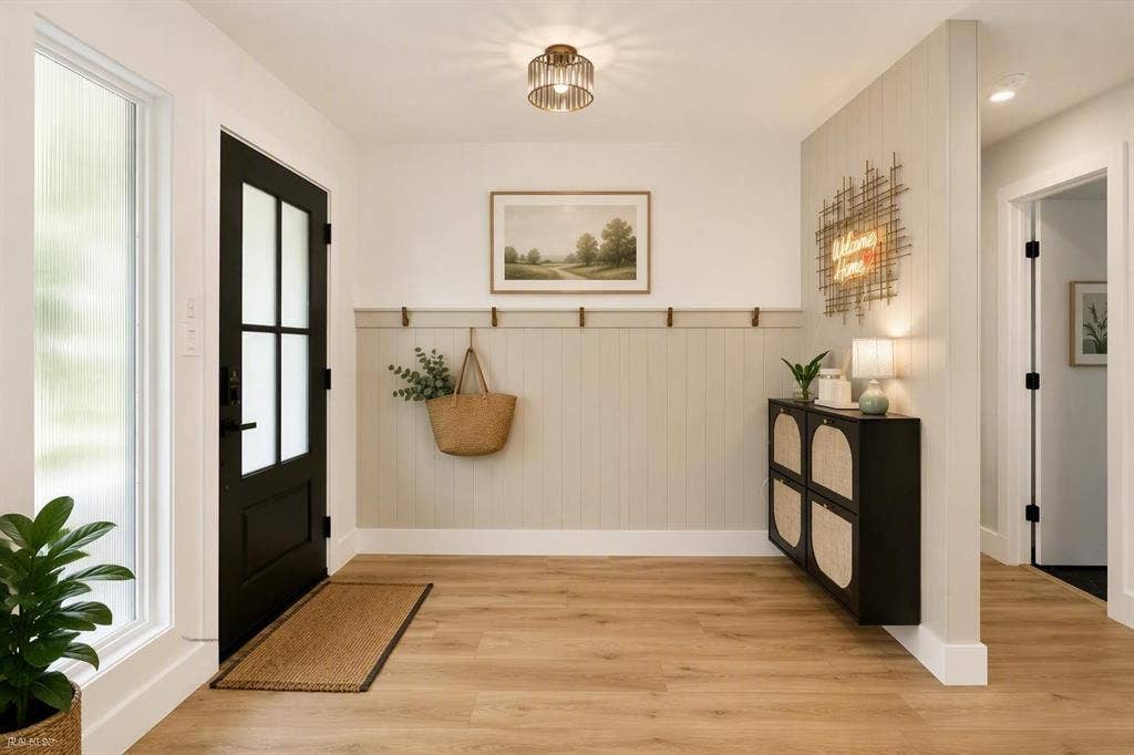 Entryway featuring wood-finish flooring, vertical shiplap wall detailing with built-in coat hooks, a glass-panel entry door, and a drum-style ceiling light fixture