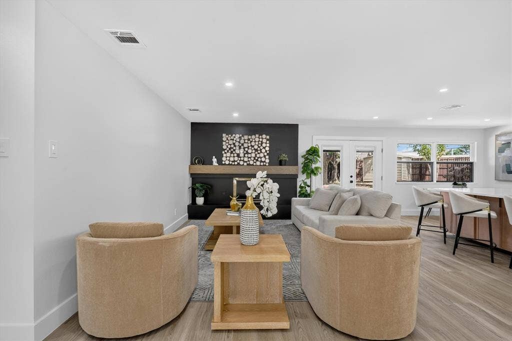 Open-concept room featuring wood-finish flooring, recessed lighting, and a floor-to-ceiling accent wall with a built-in fireplace and floating mantle