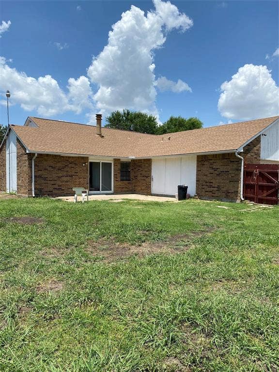 902 Maydelle Lane, Garland, TX 75042 Exterior featuring a brick facade, concrete patio, asphalt shingle roof, and wooden privacy fencing