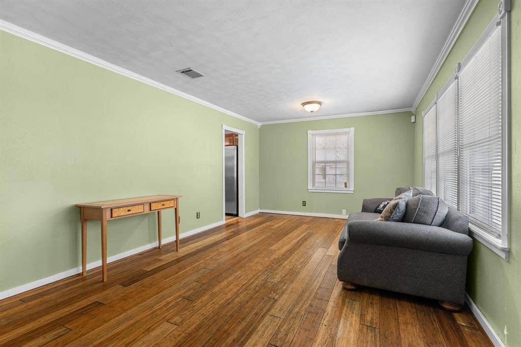 920 Avenue C, Lacy Lakeview, TX 76705 Living area featuring wood-finish flooring, crown molding, and dual windows with horizontal blinds