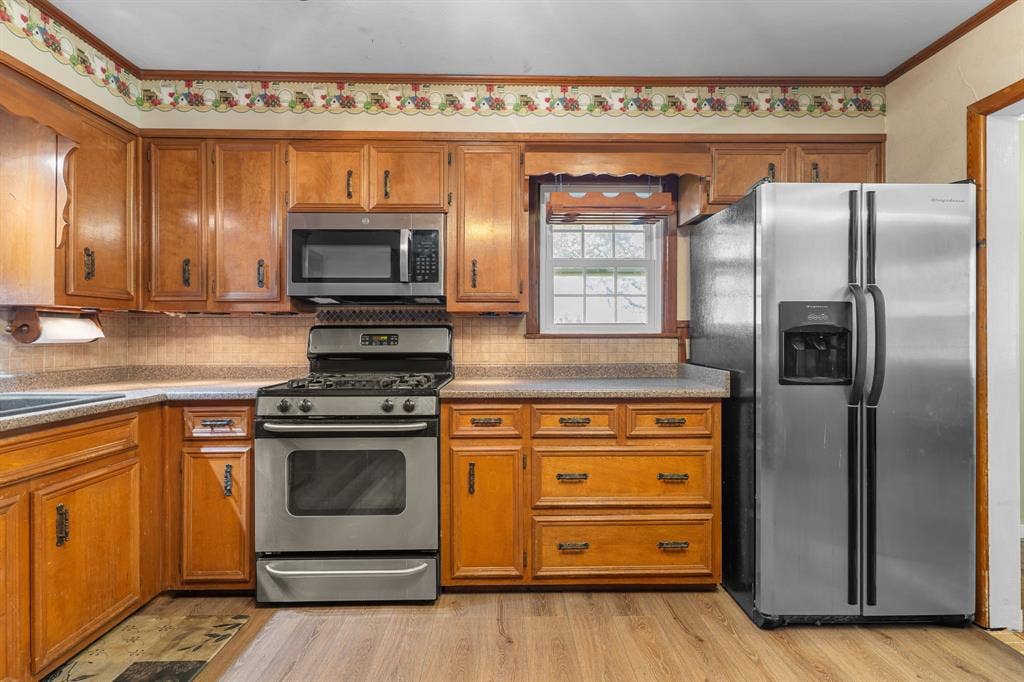 920 Avenue C, Lacy Lakeview, TX 76705 Kitchen featuring wood cabinetry, stainless steel gas range, built-in microwave, stainless steel refrigerator, and wood-finish flooring