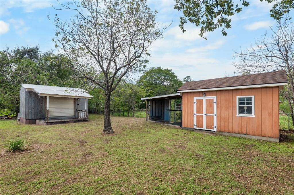 920 Avenue C, Lacy Lakeview, TX 76705 Expansive grounds featuring two storage structures, a covered exterior stall, and mature trees
