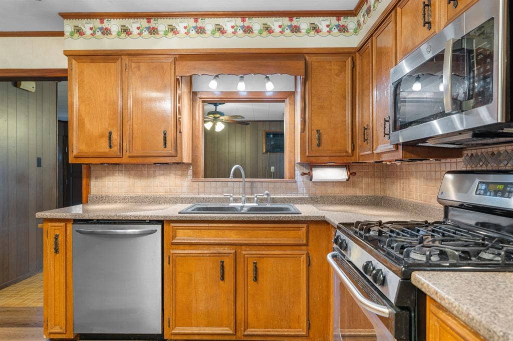 920 Avenue C, Lacy Lakeview, TX 76705 Kitchen featuring wood cabinetry, stainless steel appliances, a gas range, a dual-basin sink, and tile backsplash