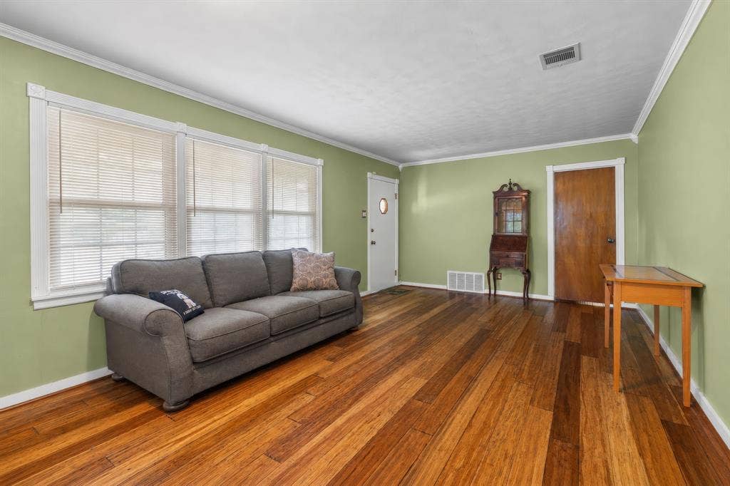 920 Avenue C, Lacy Lakeview, TX 76705 Living area featuring wood-finish flooring, crisp crown molding, and large multi-pane windows with horizontal blinds