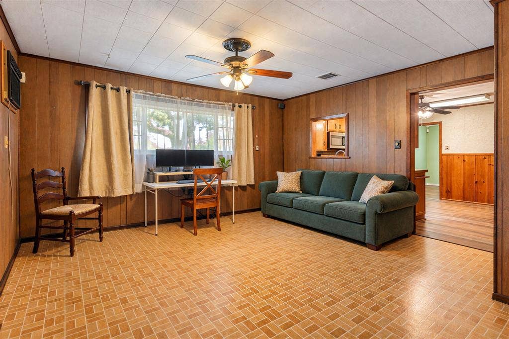920 Avenue C, Lacy Lakeview, TX 76705 Wood-paneled walls, tile flooring, ceiling fan with integrated lighting, and a kitchen passthrough window