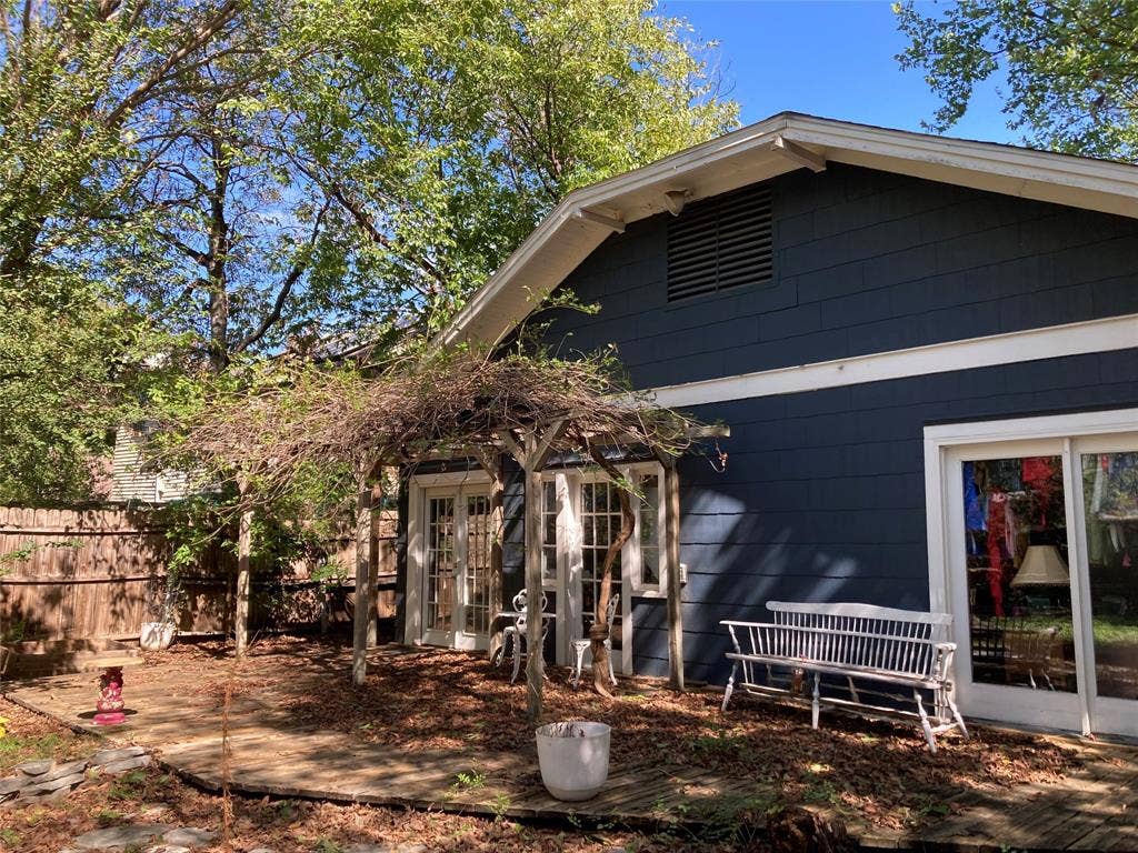Rear exterior featuring dark-toned shake siding, a wooden pergola, sliding glass doors, and a wood-decking patio