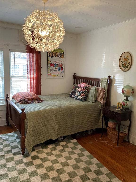 Room featuring hardwood flooring, multi-pane windows with integrated blinds, and a statement spherical chandelier