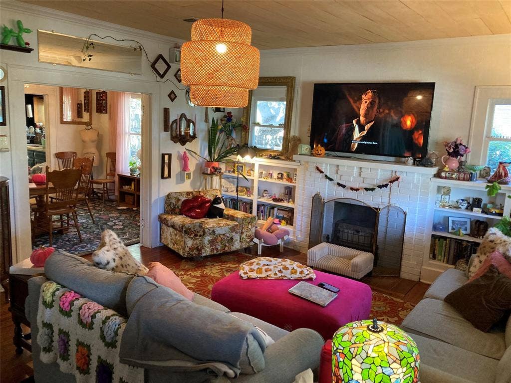 Living space featuring a brick fireplace with a mantel, built-in shelving, wood-plank ceiling, and a woven pendant light fixture