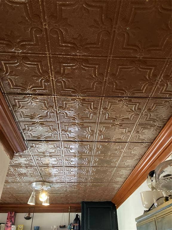 Metallic-finish pressed tin ceiling featuring ornate geometric tile patterns and a polished crown molding border