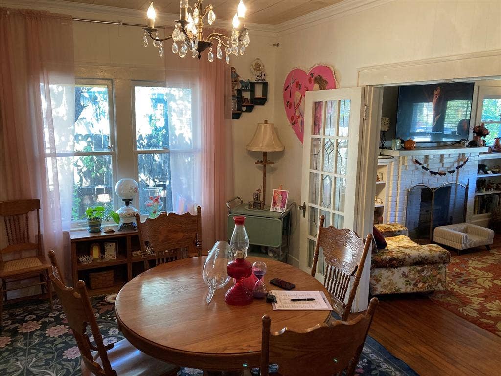 Dining area featuring a multi-light crystal chandelier, wood-finish flooring, dual windows, and a multi-pane glass French door