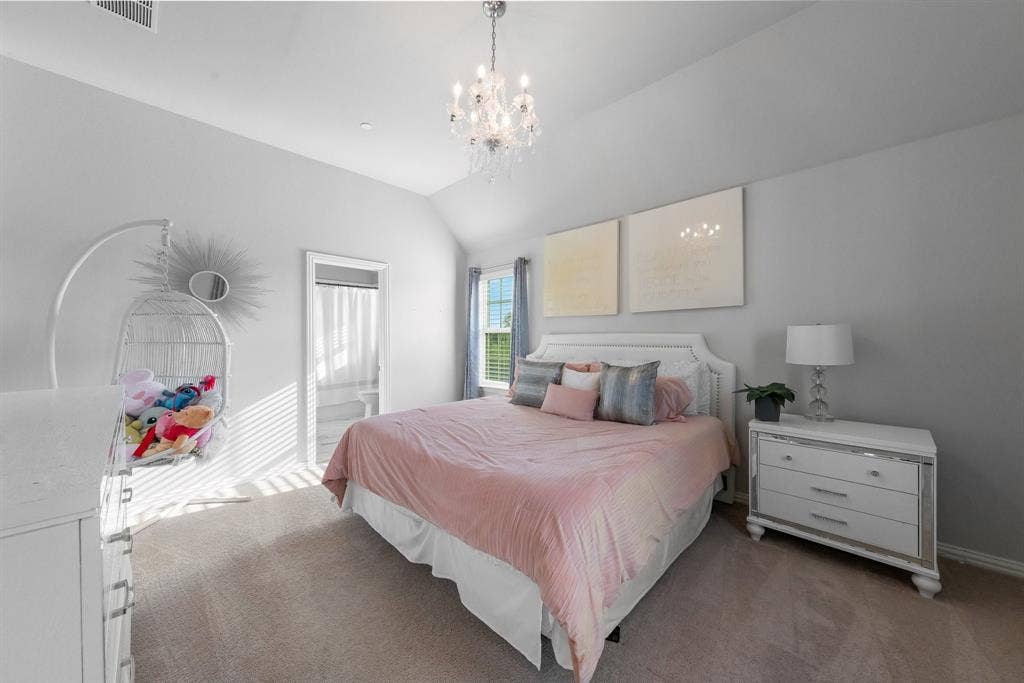 Vaulted ceilings, crystal chandelier, neutral wall color, and window with natural light