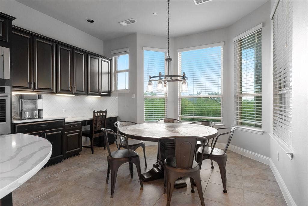 Kitchen featuring dark finish cabinetry, built-in desk, stone-surface countertops, tile flooring, and a bay window configuration
