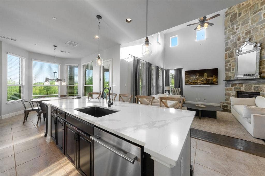 Kitchen island featuring a stone-surface countertop, under-mount sink, and dark cabinetry