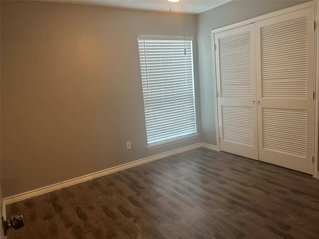 1314 Frio Lane, Garland, TX 75040 Wood-finish flooring, neutral wall tones, louvered-style double closet doors, and a window fitted with horizontal blinds