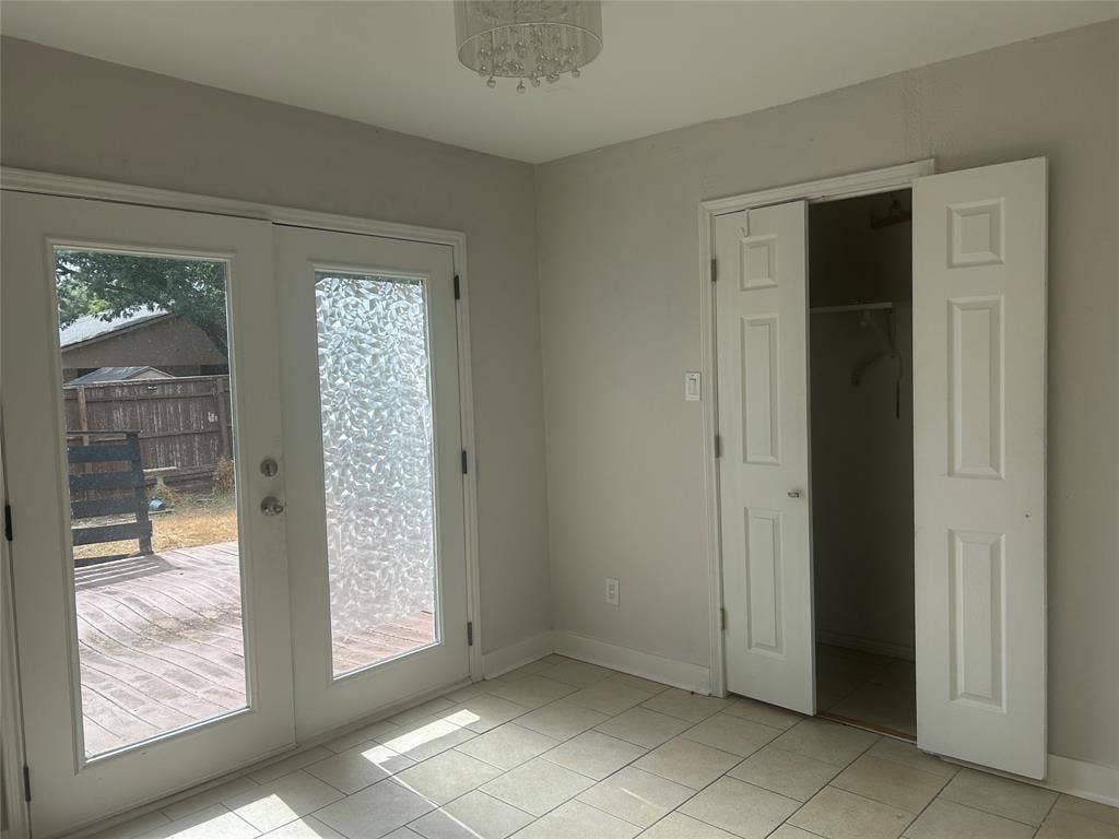 1314 Frio Lane, Garland, TX 75040 Double-door glass entry featuring textured privacy panels, tile flooring, built-in closet with six-panel doors, and a decorative flush-mount ceiling fixture